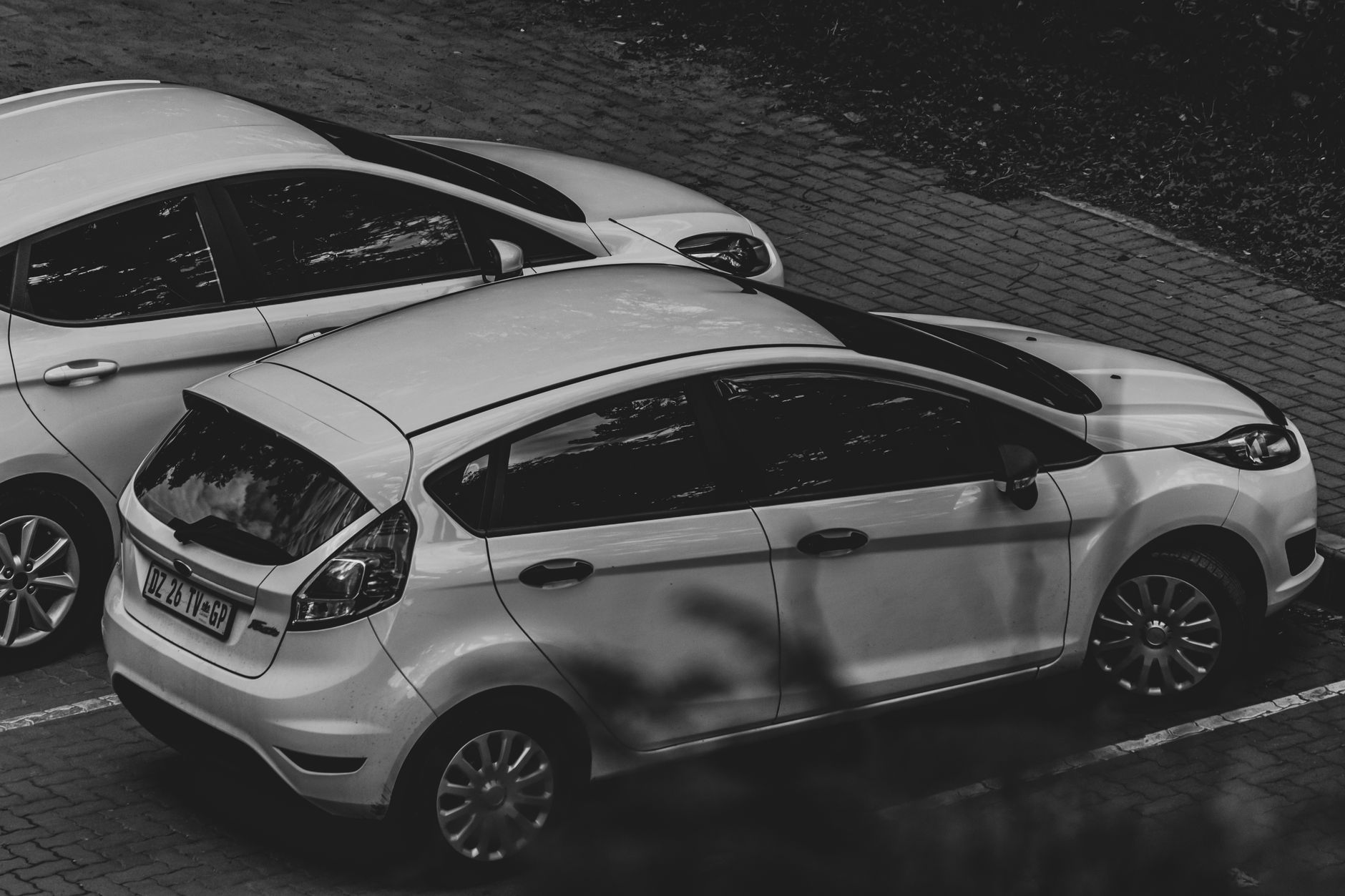 A monochrome image showcasing parked cars in an urban environment. — Why you need that car window tinted